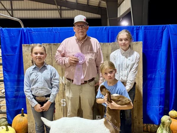 Youth exhibitors with a goat and a purple ribbon at the West Tennessee State Fair